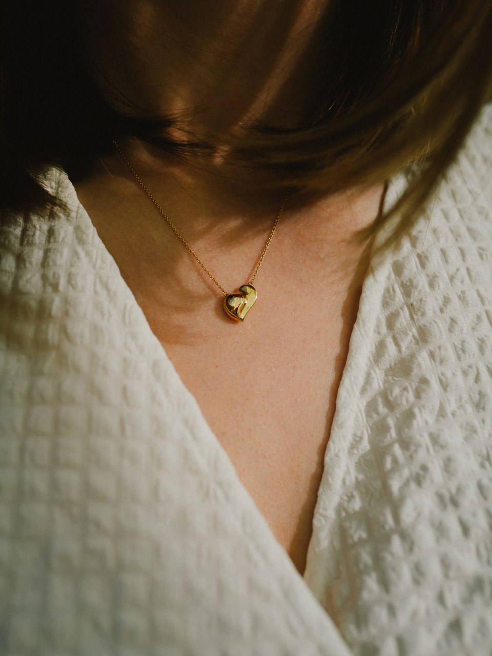 Gold heart pendant against a white waffle-knit robe